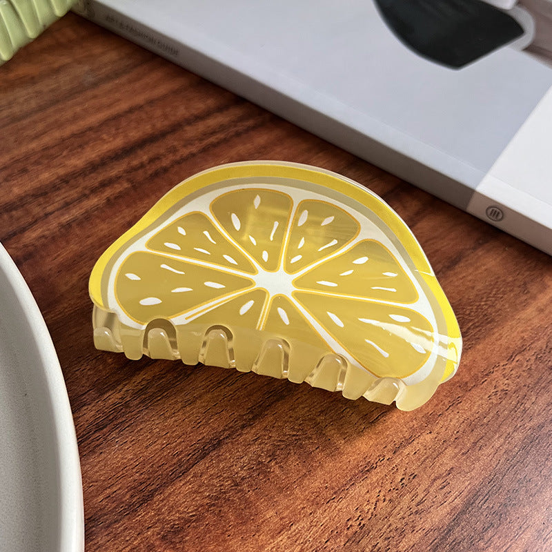 Translucent yellow acrylic hair claw shaped like a citrus slice, featuring white segment detailing.