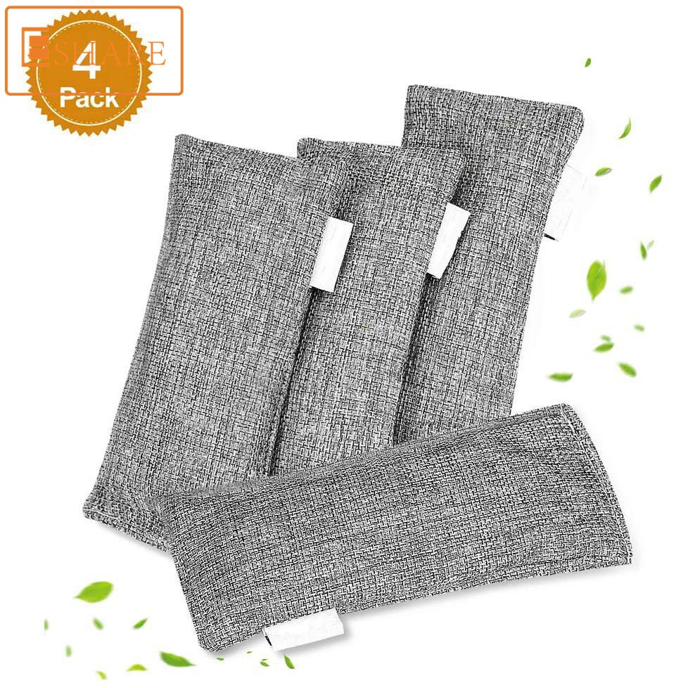 Four grey, textured fabric bamboo charcoal air purifying bags with white labels, accented by small floating green leaves.
